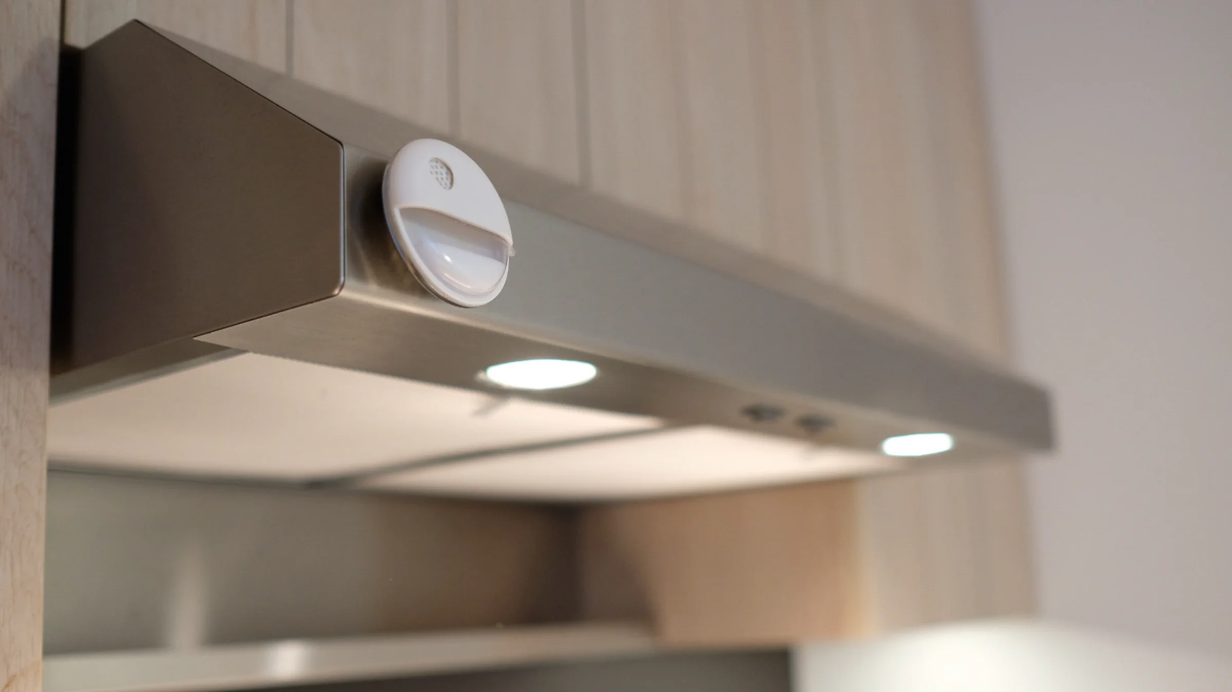 The container magnetically attached beneath a stainless-steel range hood.
